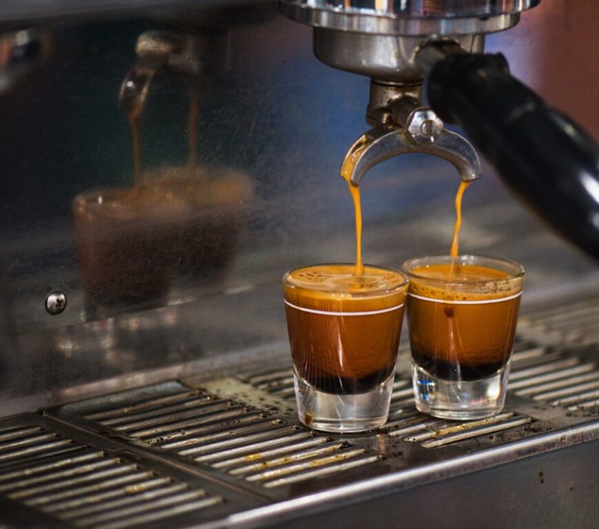 Podwójne espresso wypływające z kolby ekspresu do dwóch szklanek